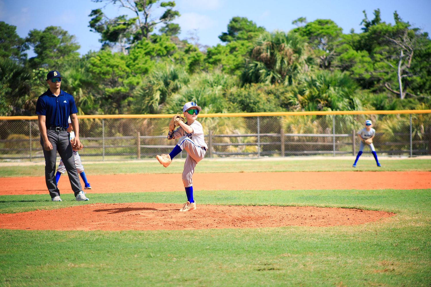 Baseball pitcher in mid-delivery motion during game on well-maintained field.