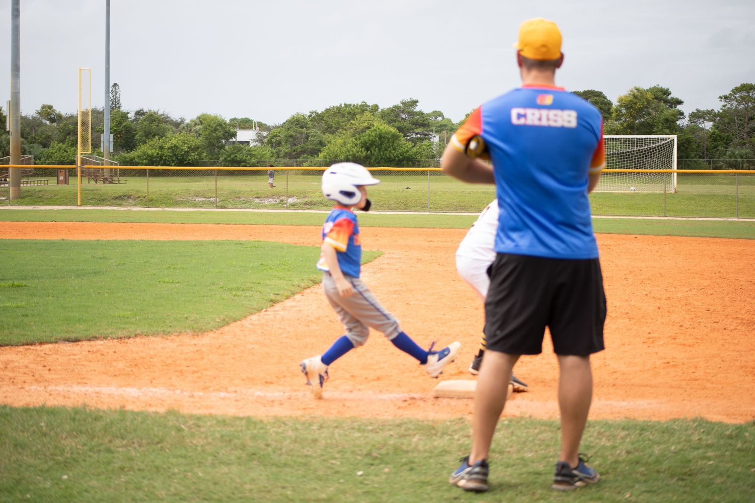 Youth baseball practice with coach instructing player on batting technique.