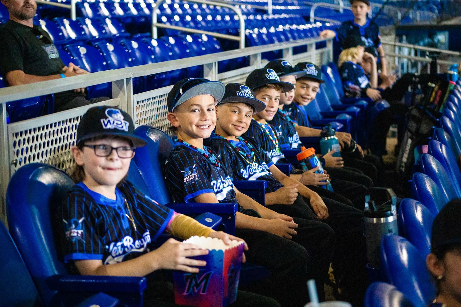 Young baseball fans sitting together in blue stadium seats enjoying the game.