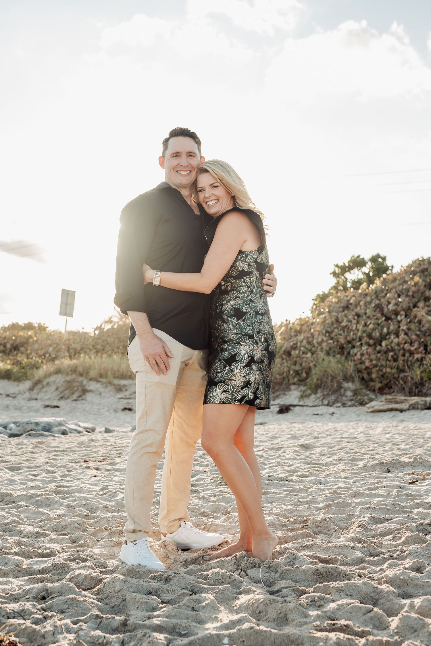 Happy couple embracing on beach during golden hour portrait session.