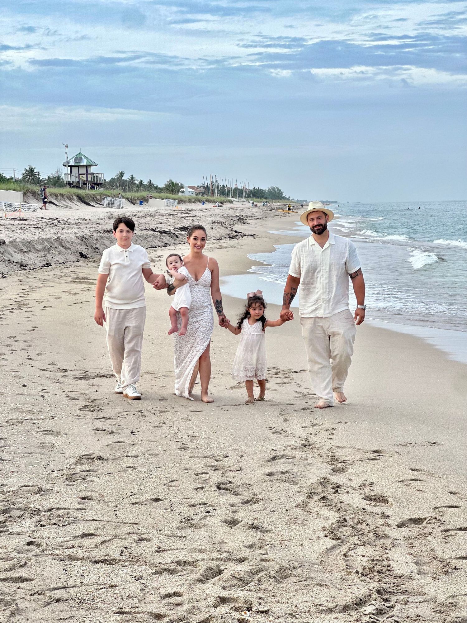Group walking together along the shoreline in coordinated white outfits.