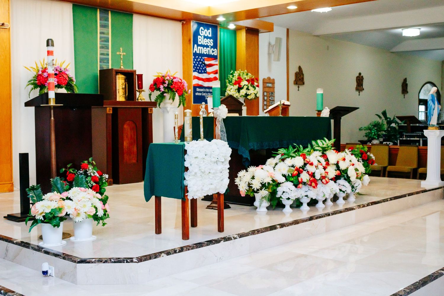 Church altar decorated with green and white floral arrangements and religious symbols.