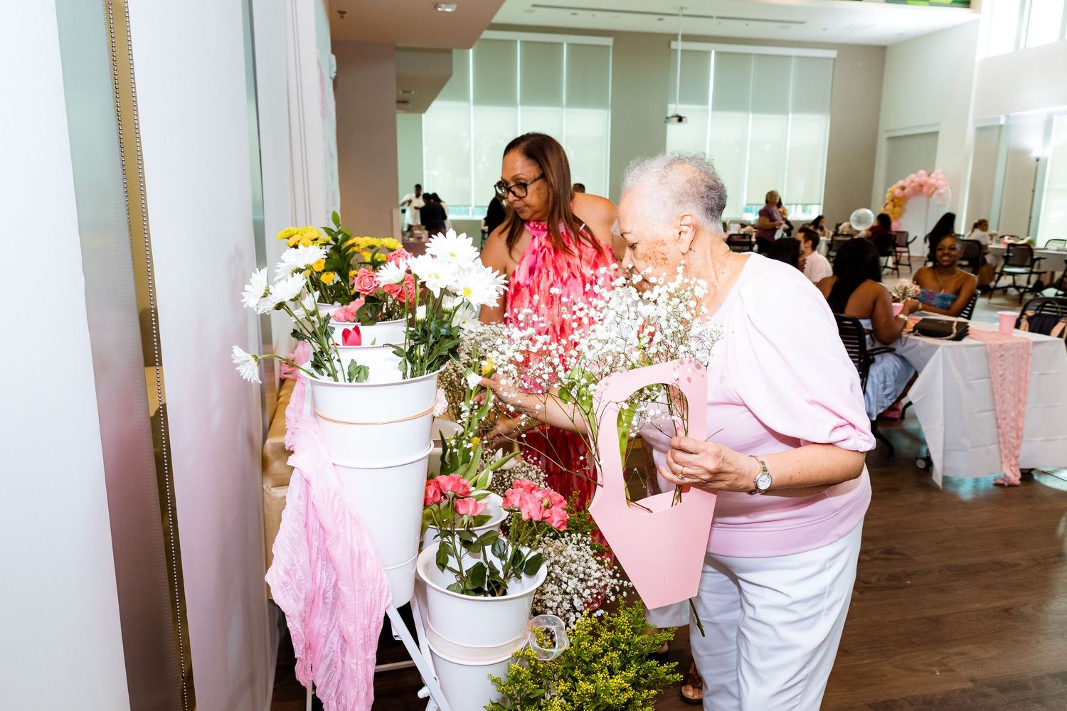 Pink floral arrangements and decor displayed at an indoor event venue.