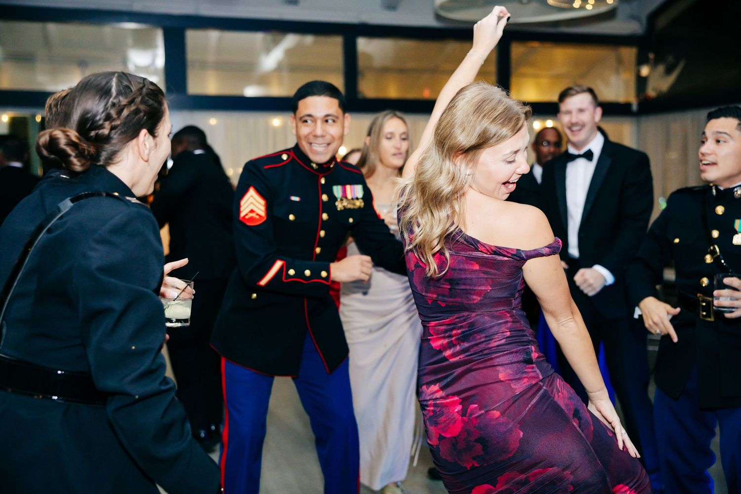 Wedding guests dance and celebrate on a dark dance floor with colorful purple lighting effects.