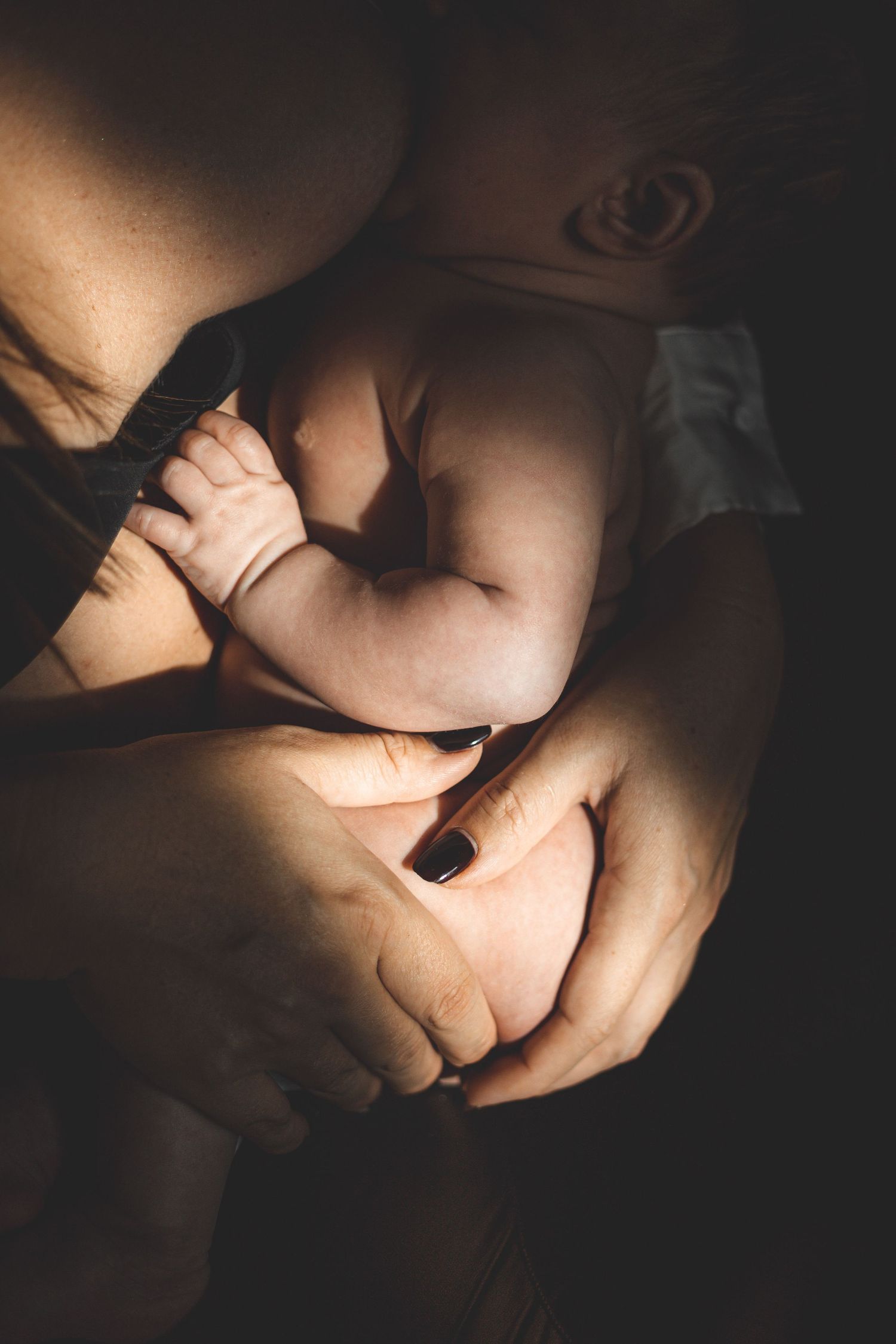 Un clair obscur laissant deviner la peau d'un bébé et de sa maman lors d'un allaitement