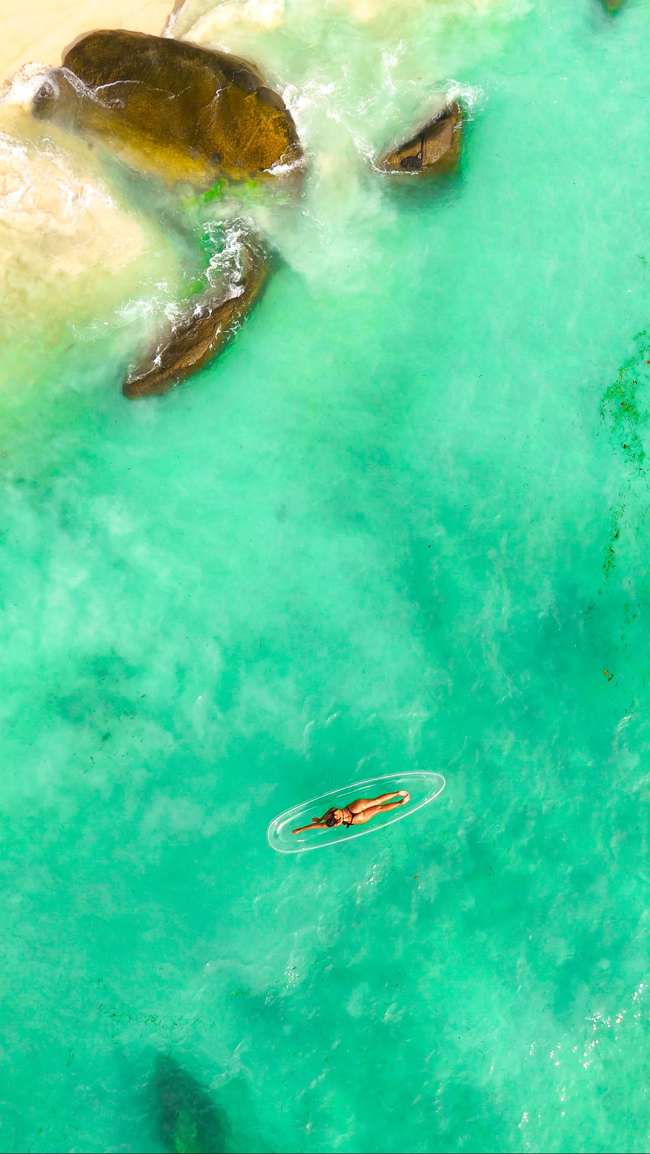 Aerial view of a clear kayak floating on turquoise tropical waters with beautiful model in the Seychelles.