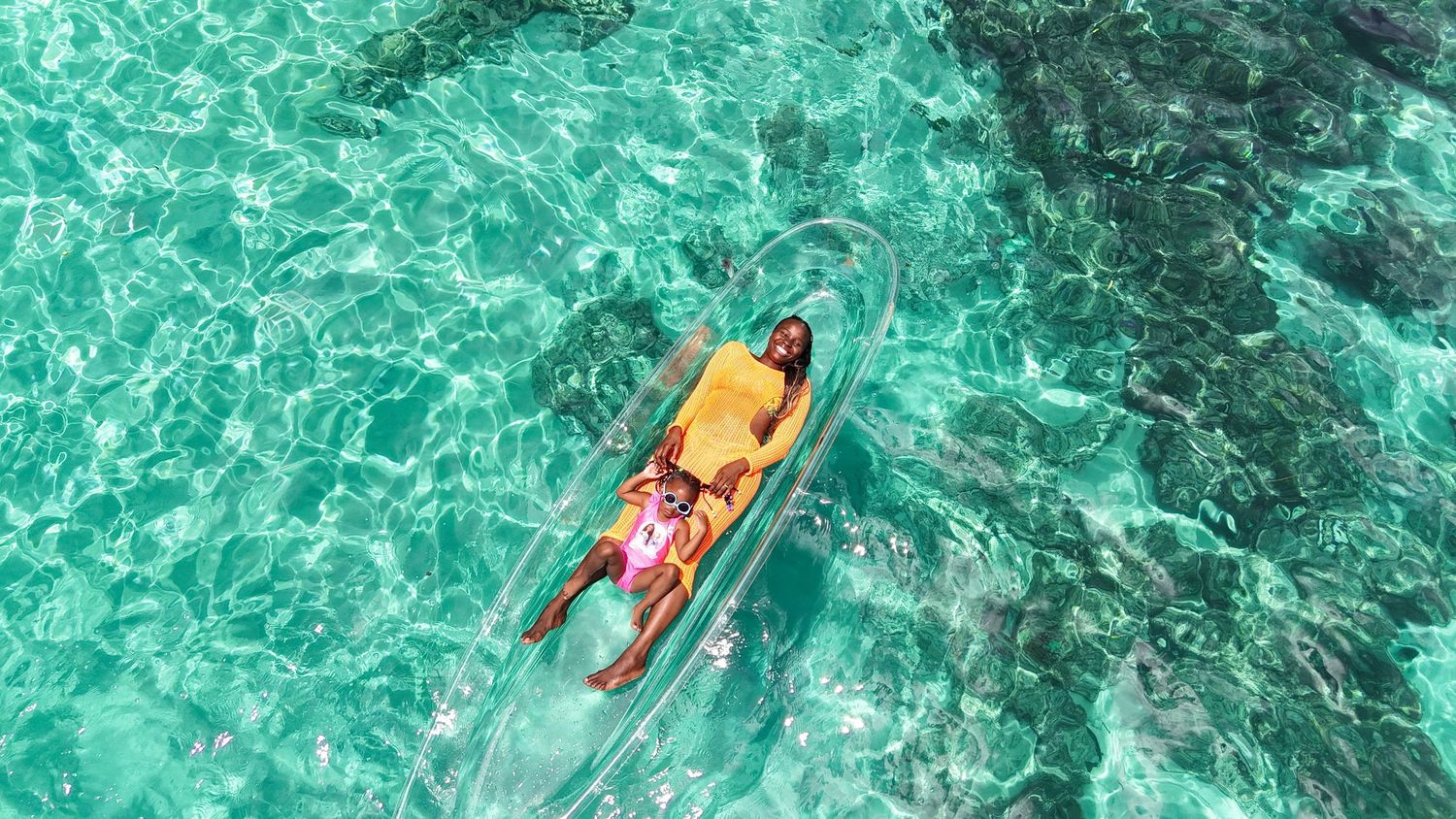 Mother and daughter clear kayak photoshoot floating in turquoise waters in the seychelles.