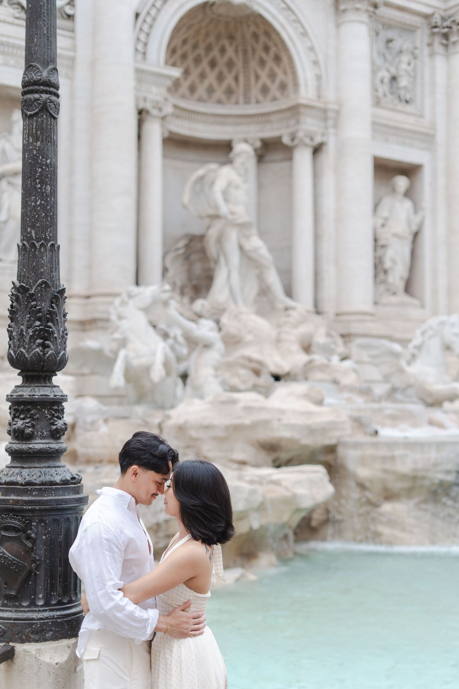 Couple embracing romantically in front of the iconic Trevi Fountain in Rome, Italy.