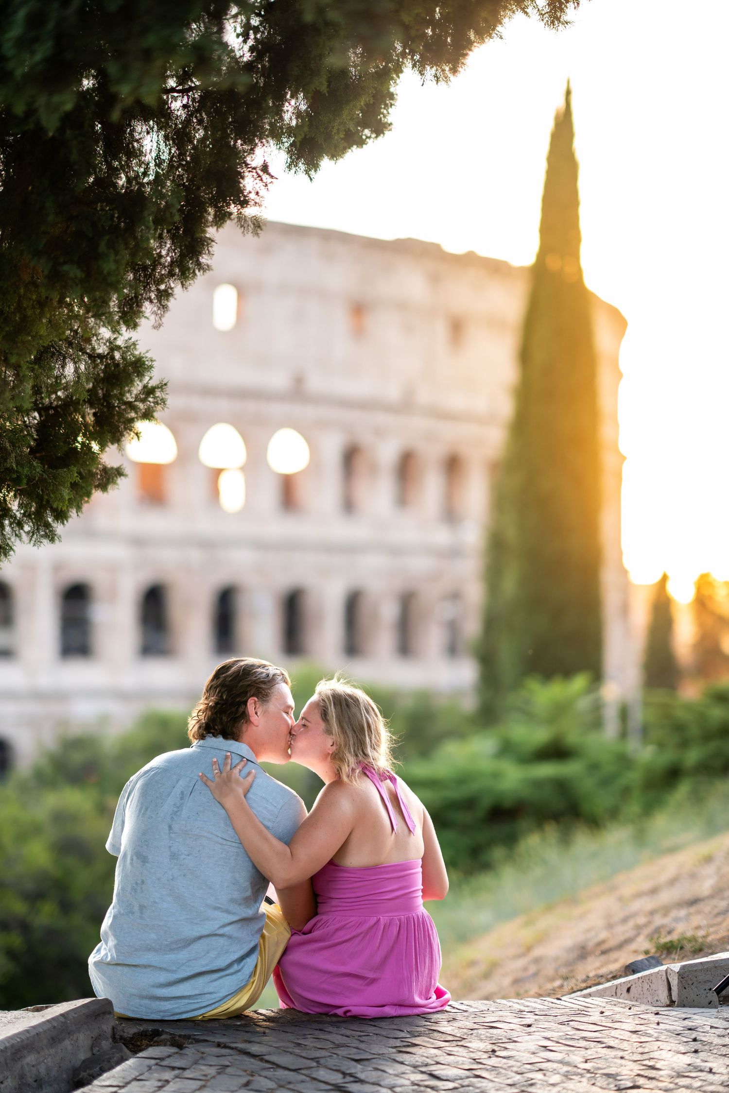 Romantic couple kissing at sunset in front of the Colosseum in Rome, Italy.