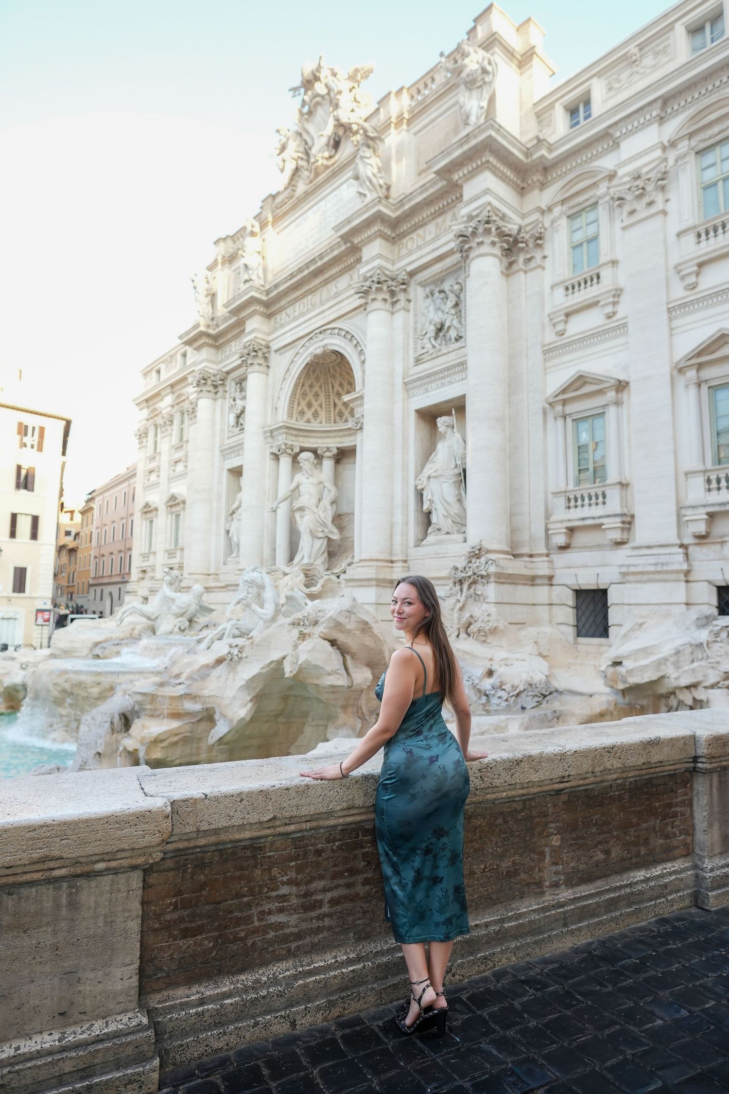 Woman in green dress posing at the Trevi Fountain in Rome, Italy.
