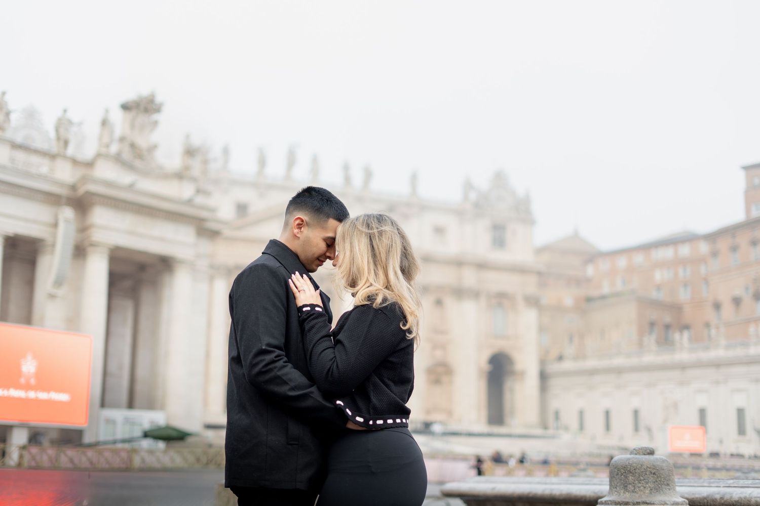 Romantic couple embracing in St. Peter's Square, Vatican City, Rome, Italy on a misty day.