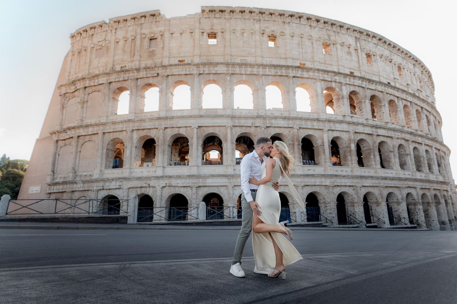 Romantic couple embracing in front of the Colosseum in Rome, Italy, during a golden hour engagement photo session.