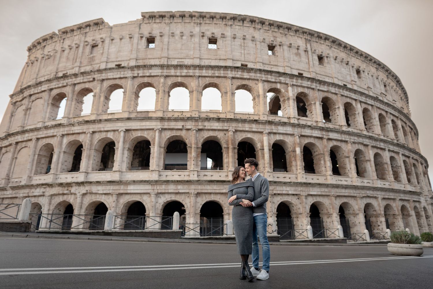 Couple embracing in front of the iconic Colosseum in Rome, Italy, with the ancient amphitheater as a backdrop.