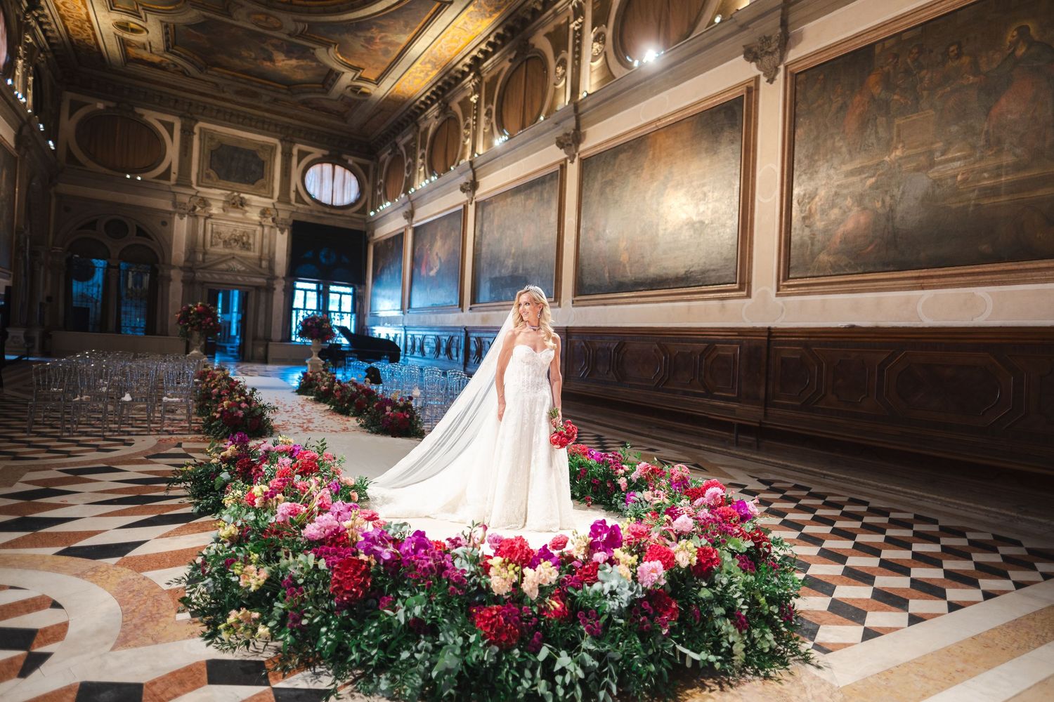 Bride in elegant gown poses within a stunning circular floral display in a grand Venetian palazzo.