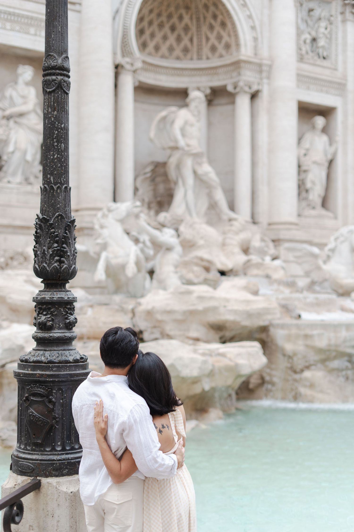 Couple embracing romantically in front of the Trevi Fountain in Rome, Italy.