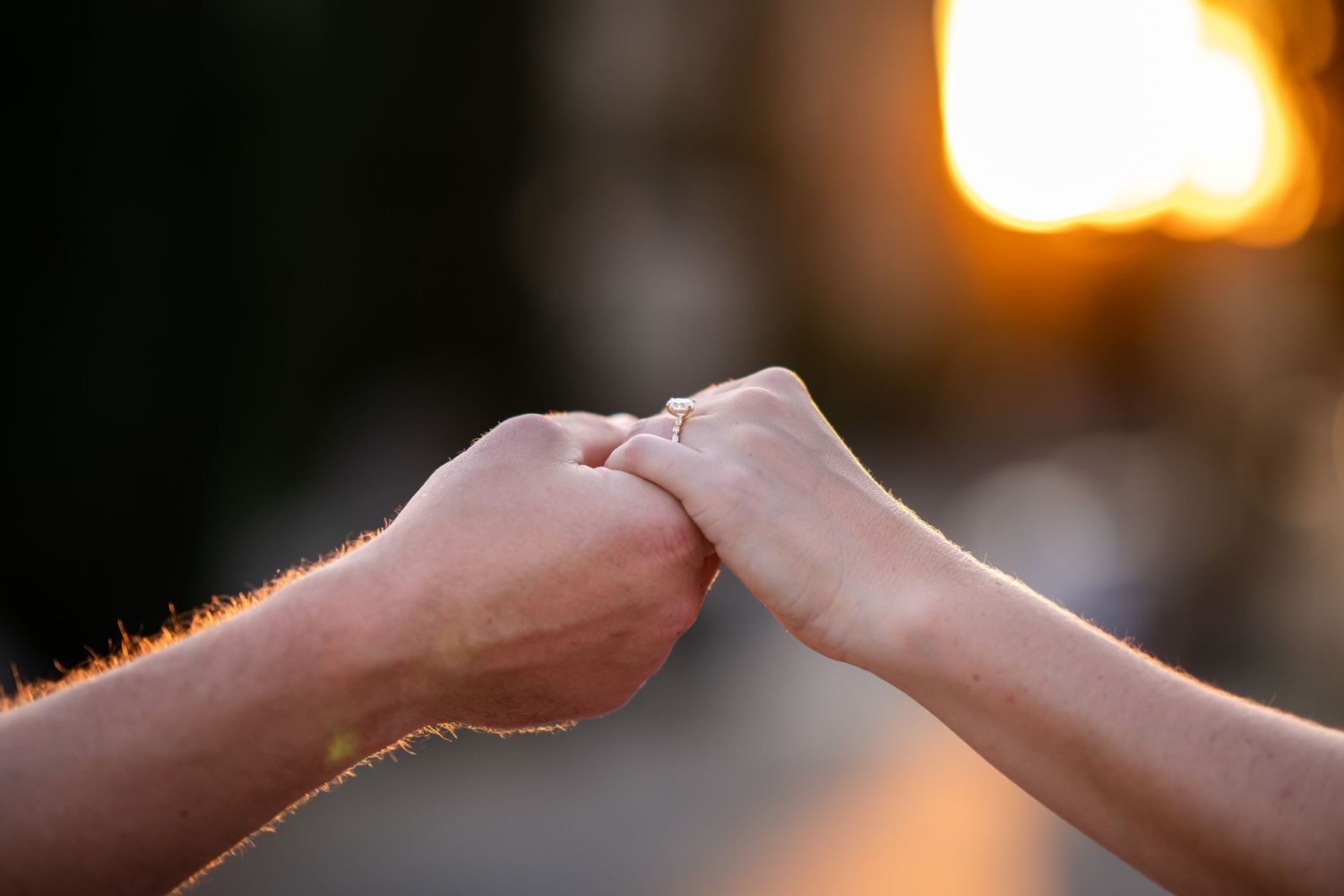 Two people sharing a fist bump at golden hour sunset, symbolizing friendship, teamwork, and connection outdoors.