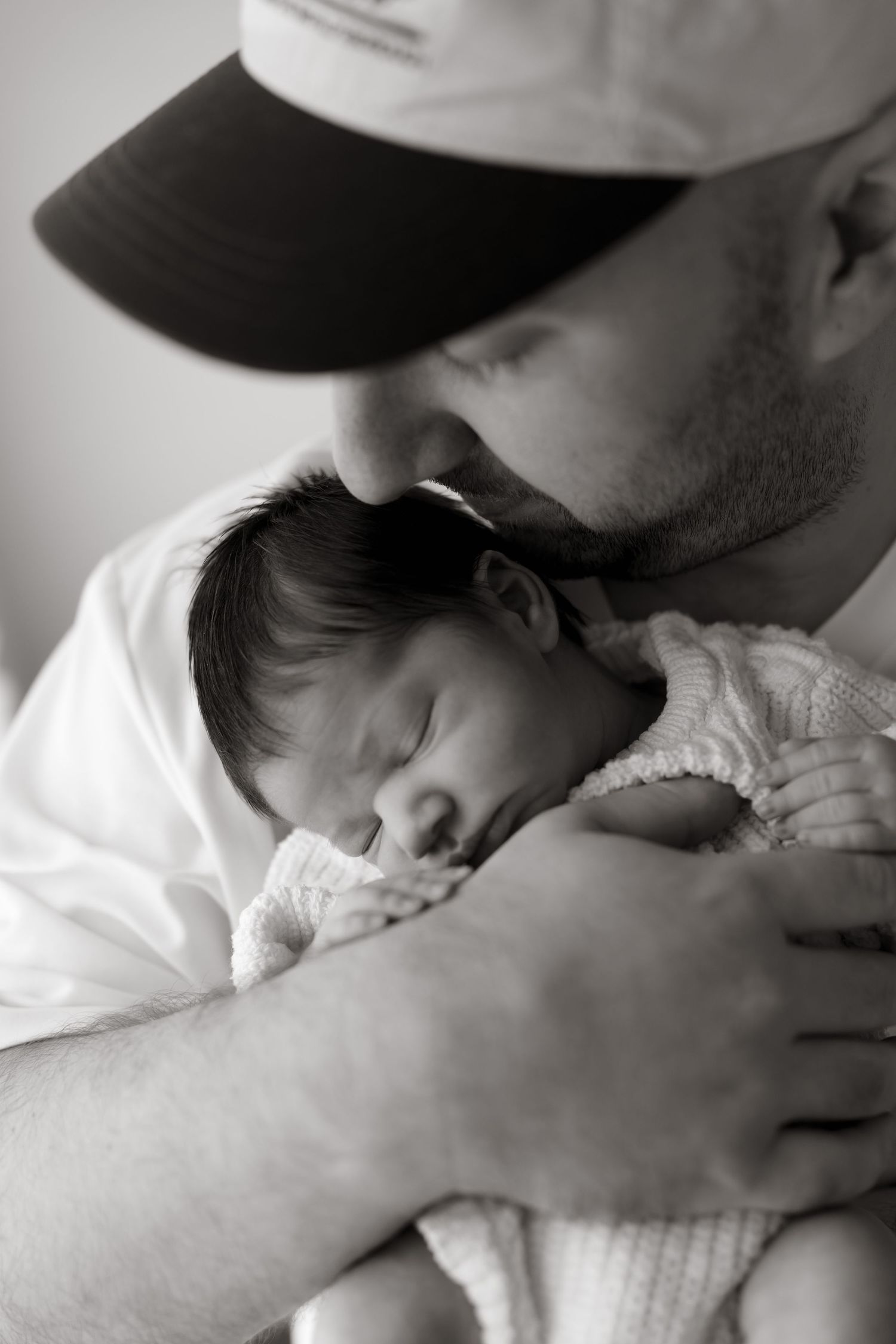 Black and white close-up of newborn baby sleeping peacefully against parent. Meg Rose Photos Perth WA.