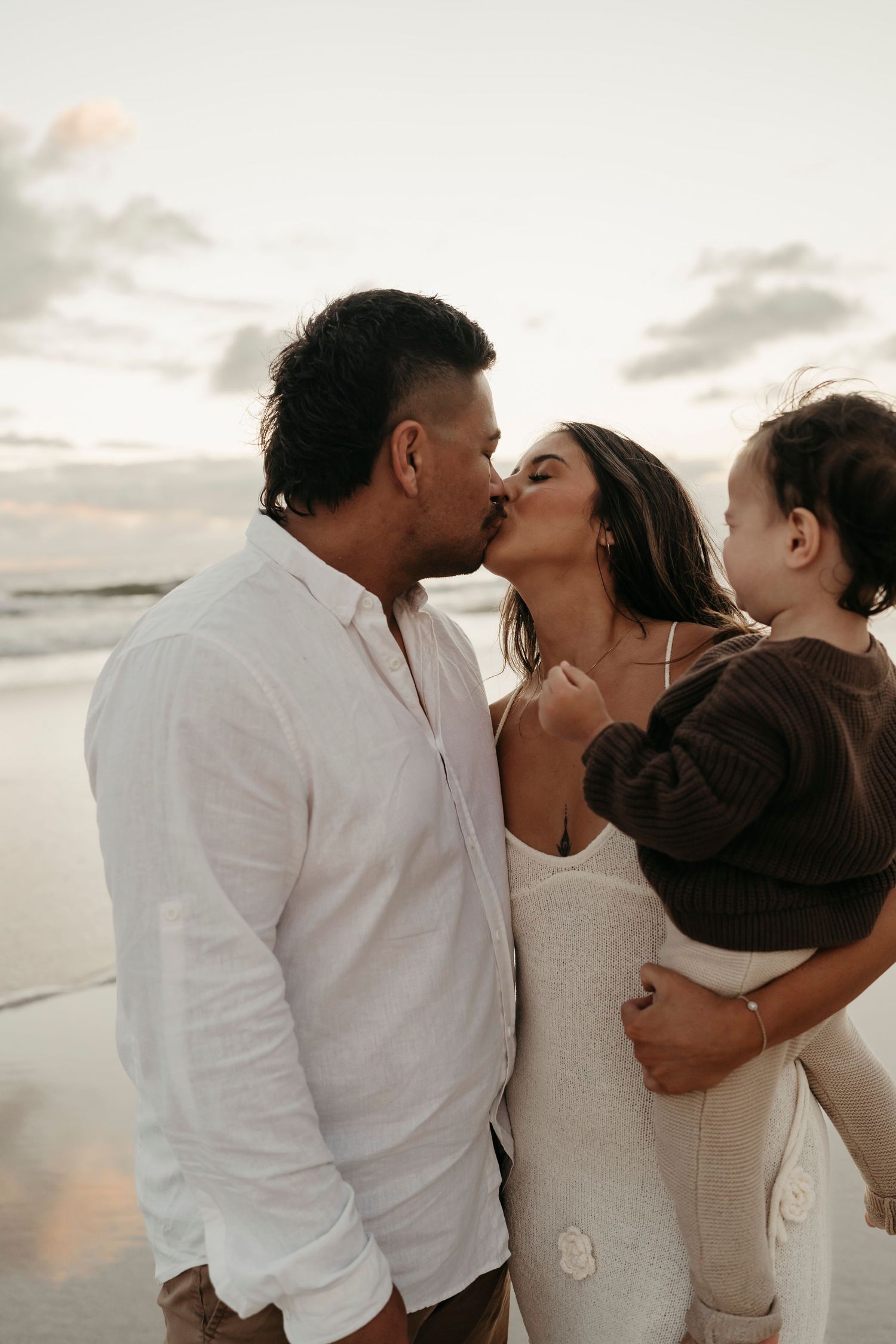 A family shares an intimate moment together on the beach at sunset.