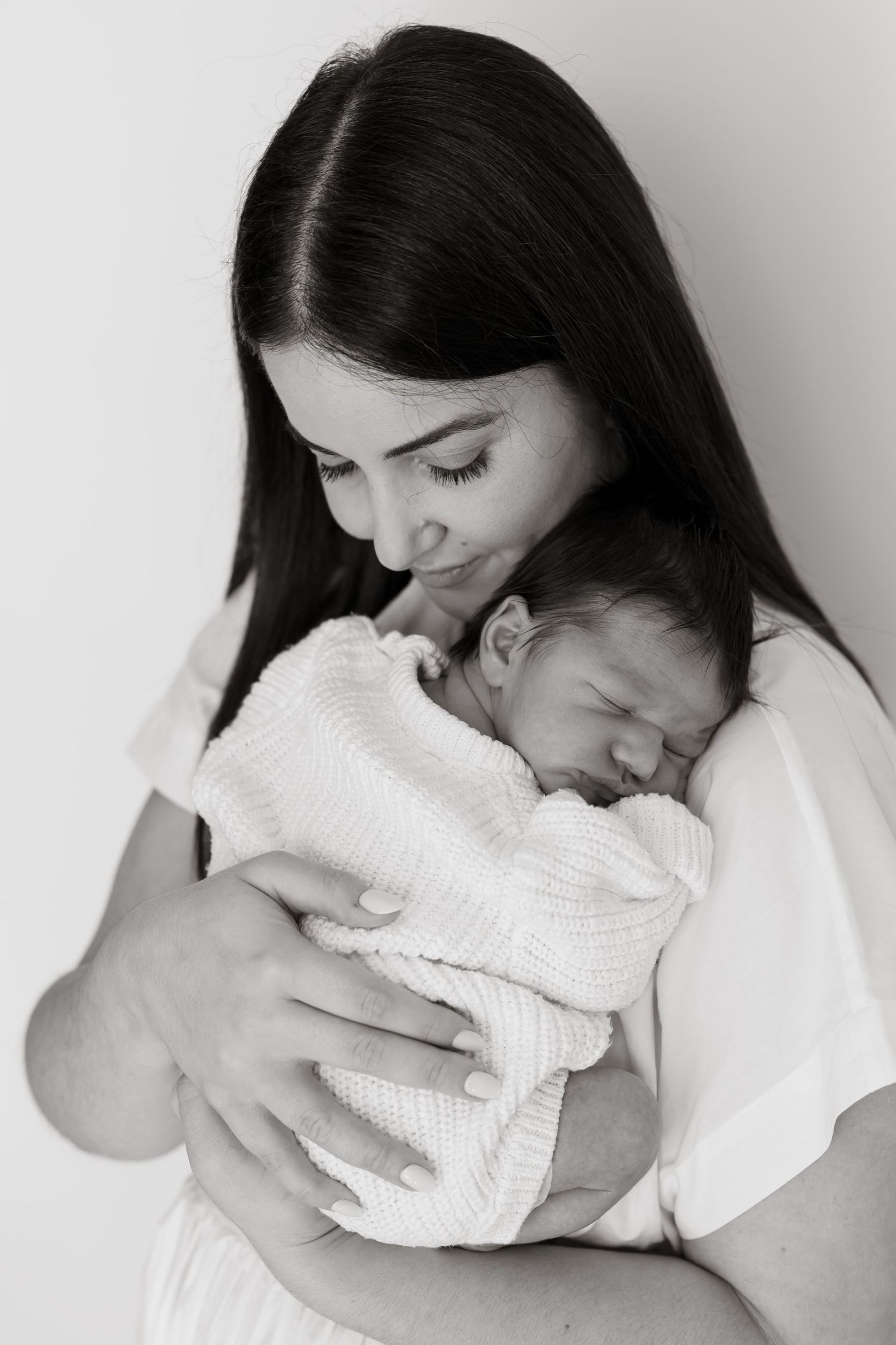 Black and white portrait capturing tender moment between mother and sleeping newborn. Meg Rose Photos Perth WA.