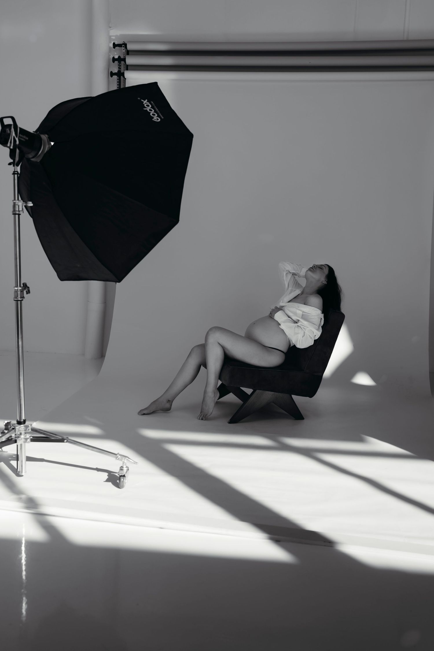 A sequence of black and white studio lighting setups showing dramatic shadows and equipment placement against a white wall.
