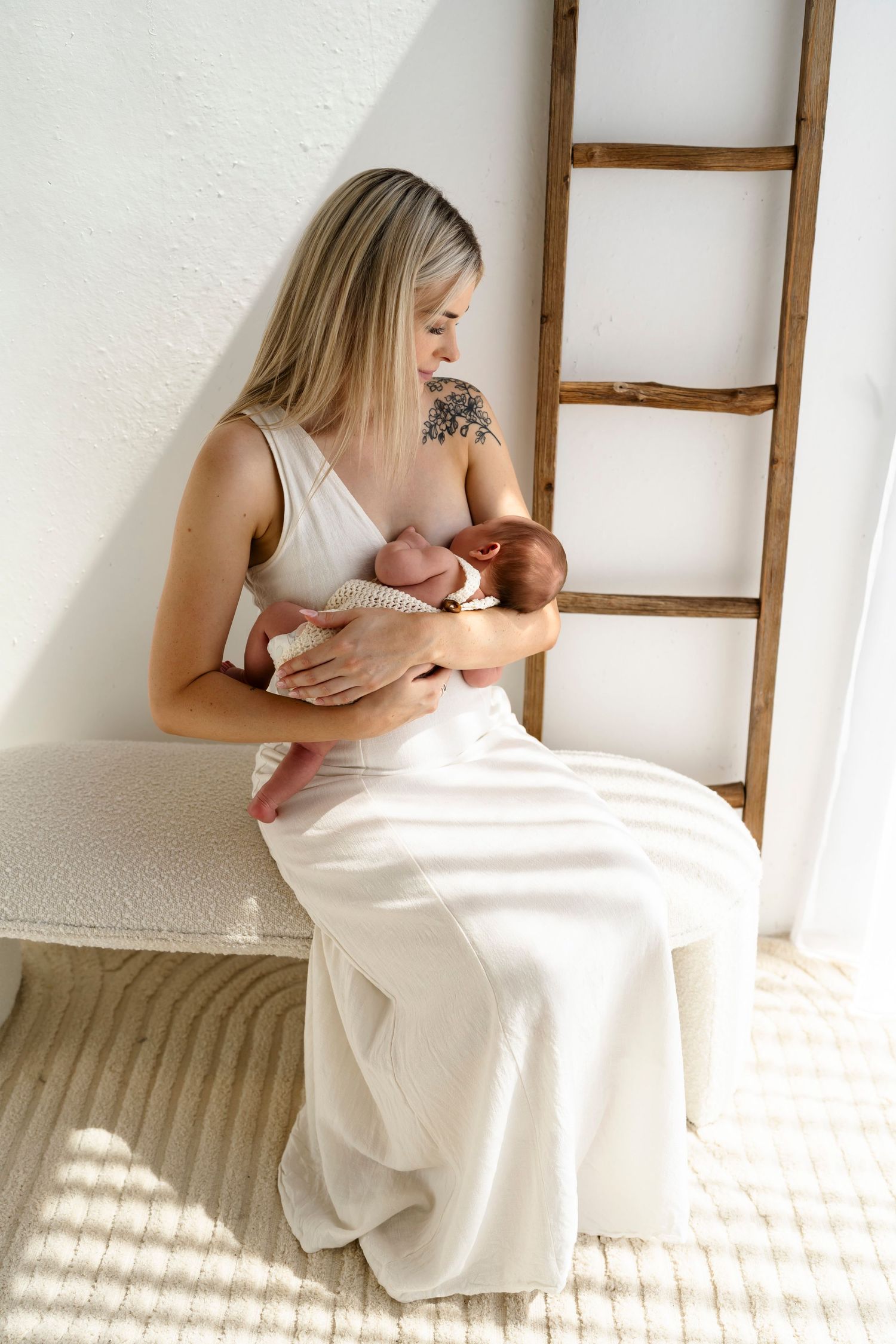 White-dressed figure embraces newborn baby in tender sequence showing tender moments across minimalist scene.