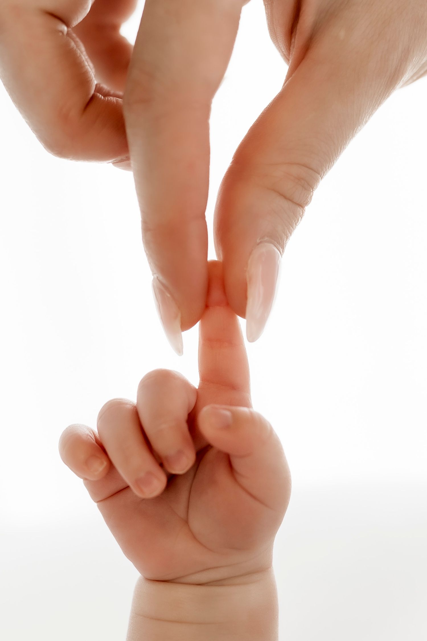 Small baby hand reaching up to touch an adult's fingers against white background.