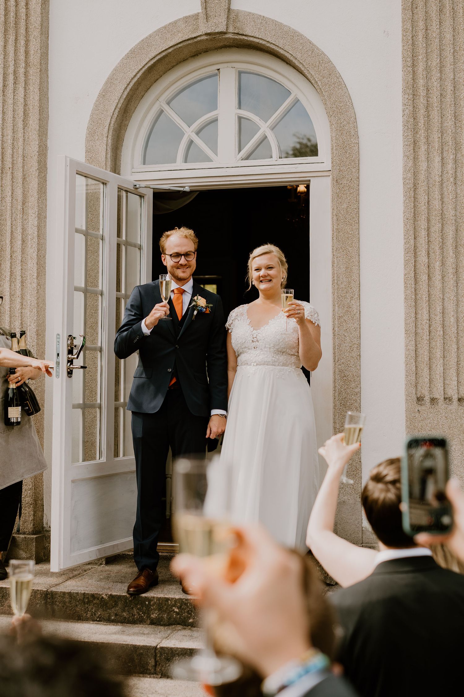 Celebratory moment captured on the steps of a historic building with arched windows and stone columns.