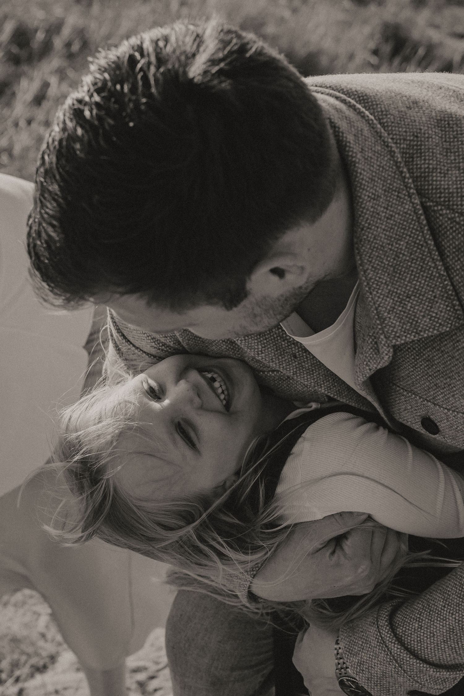 A tender black and white romantic moment captured between a couple in vintage-style clothing.