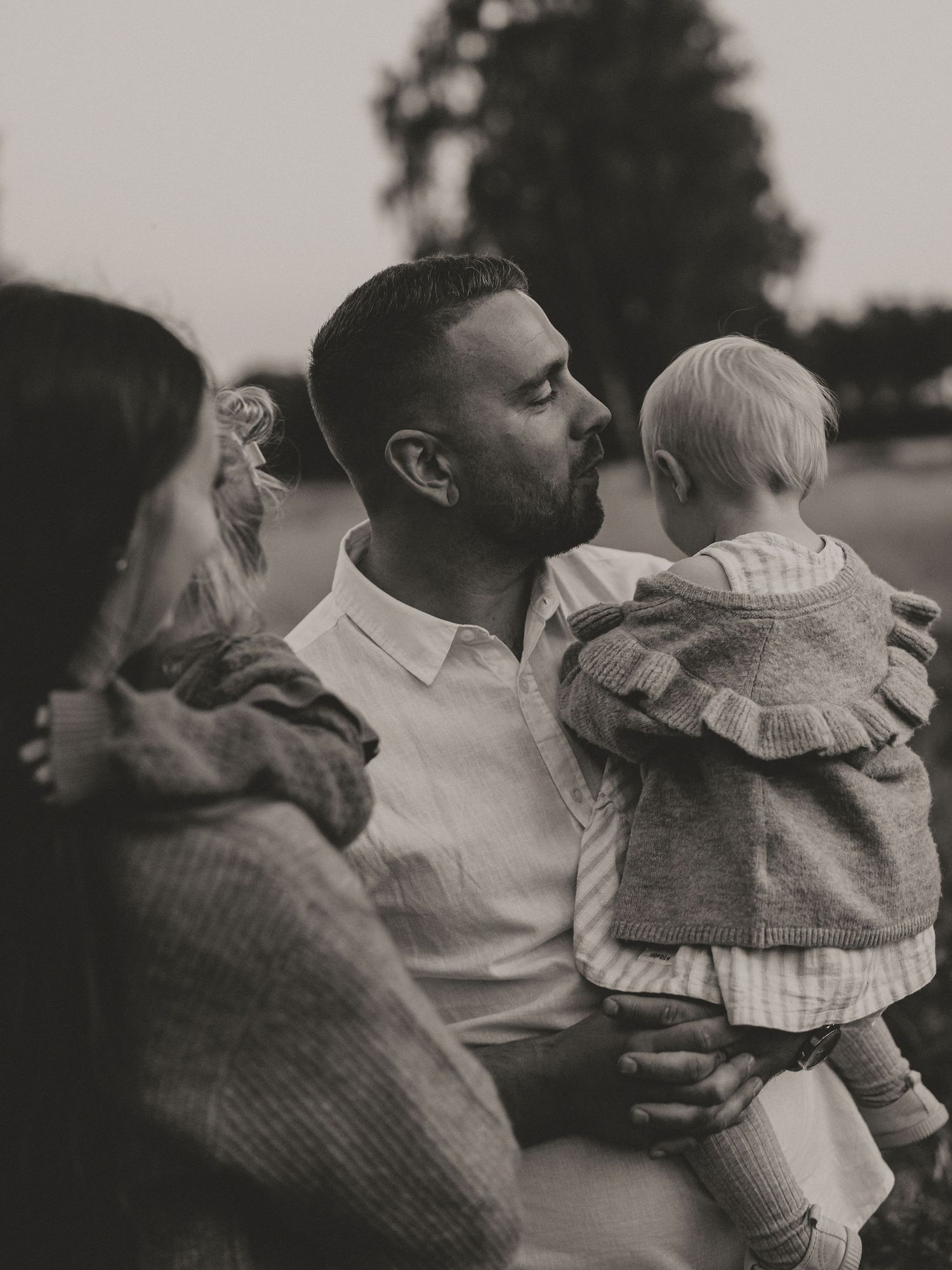 Black and white portrait of a family sharing an intimate outdoor moment.