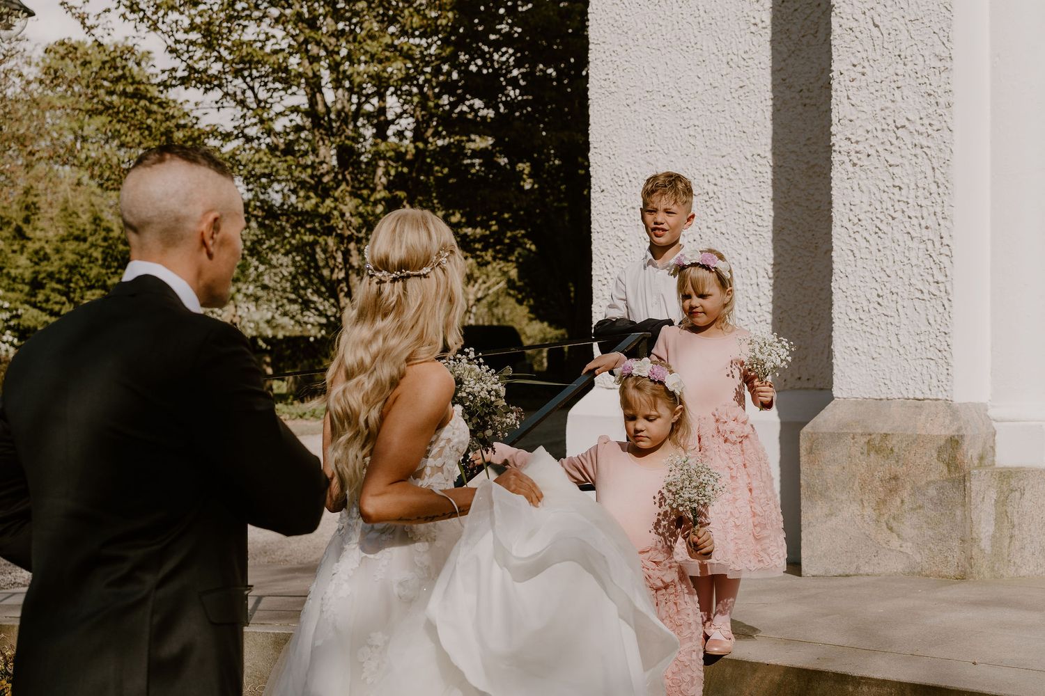 A joyful wedding ceremony moment with children watching from the white marble steps of a building.