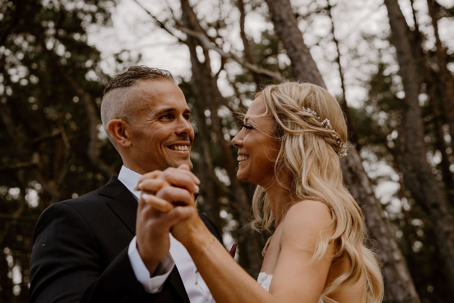 Happy bride and groom share a romantic dance together in the forest during their intimate wedding celebration.