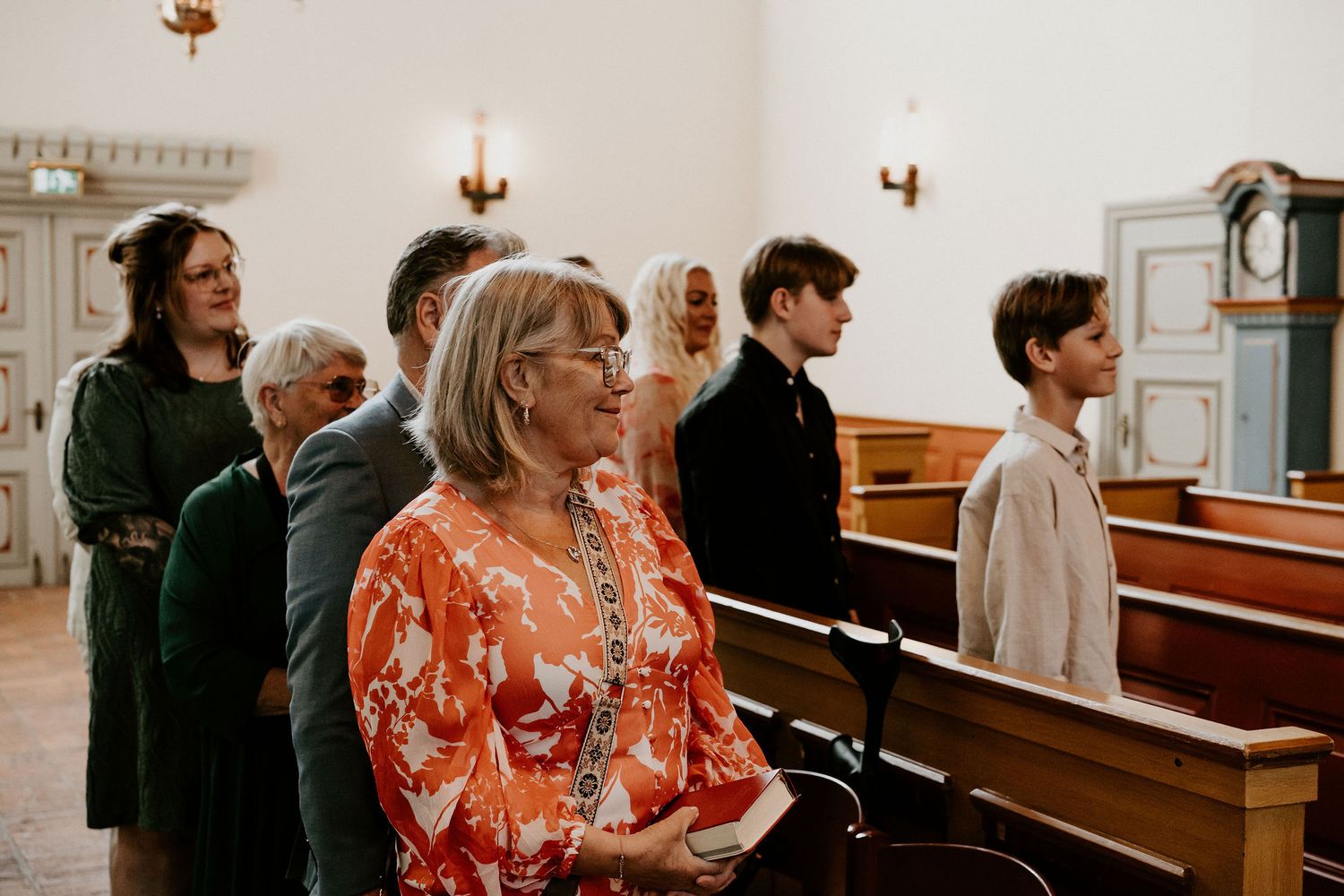 Wedding guests seated in wooden church pews during an indoor ceremony.