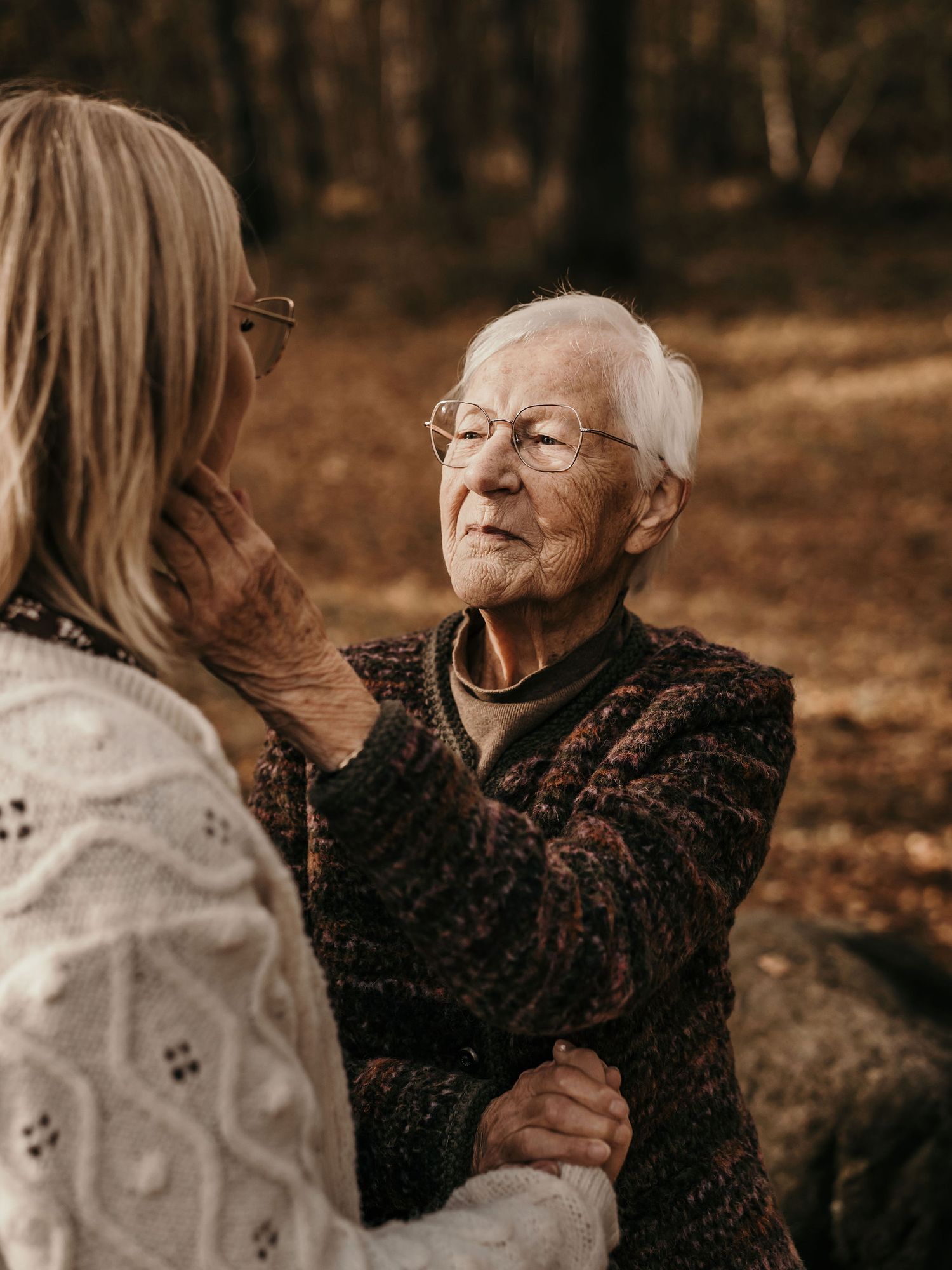 A tender heartfelt moment captured between two people sitting together outdoors in an autumn setting.