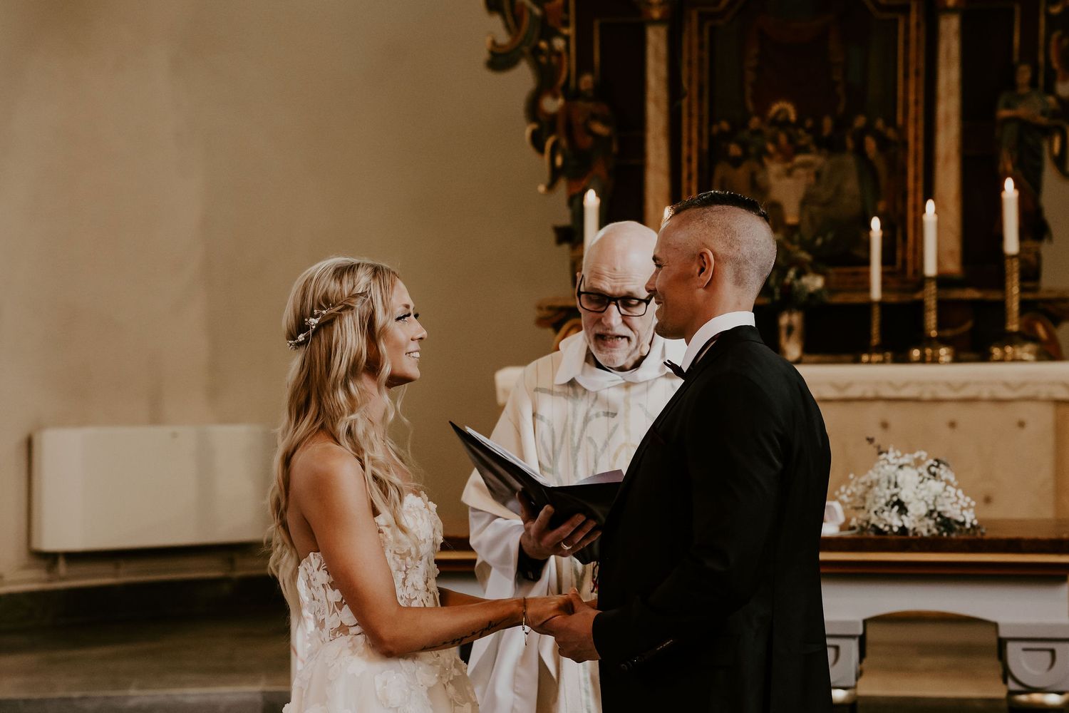 Traditional wedding ceremony taking place at the altar in an ornate church interior.