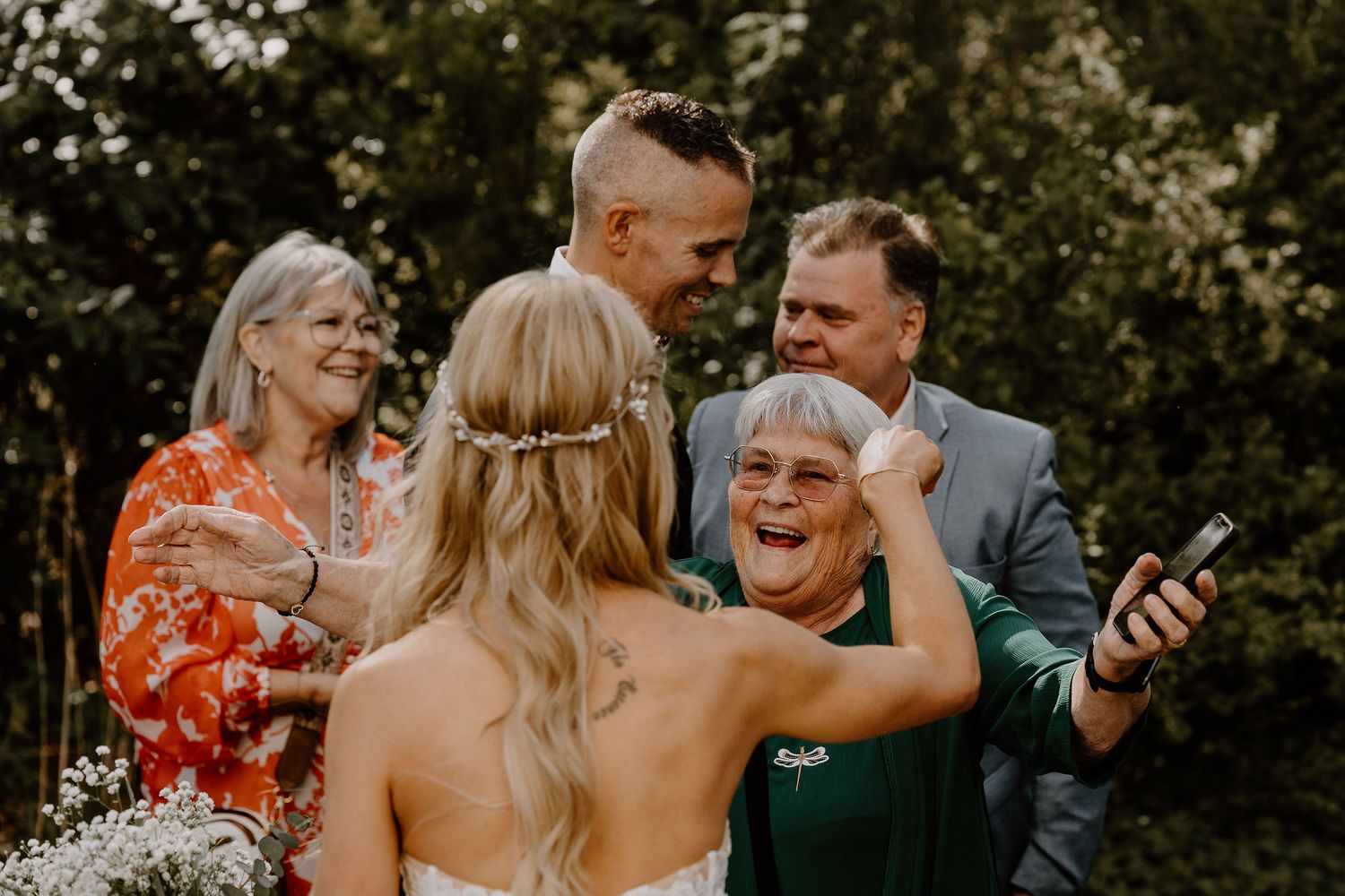 A candid moment of laughter between wedding guests and the bride during an outdoor wedding celebration.