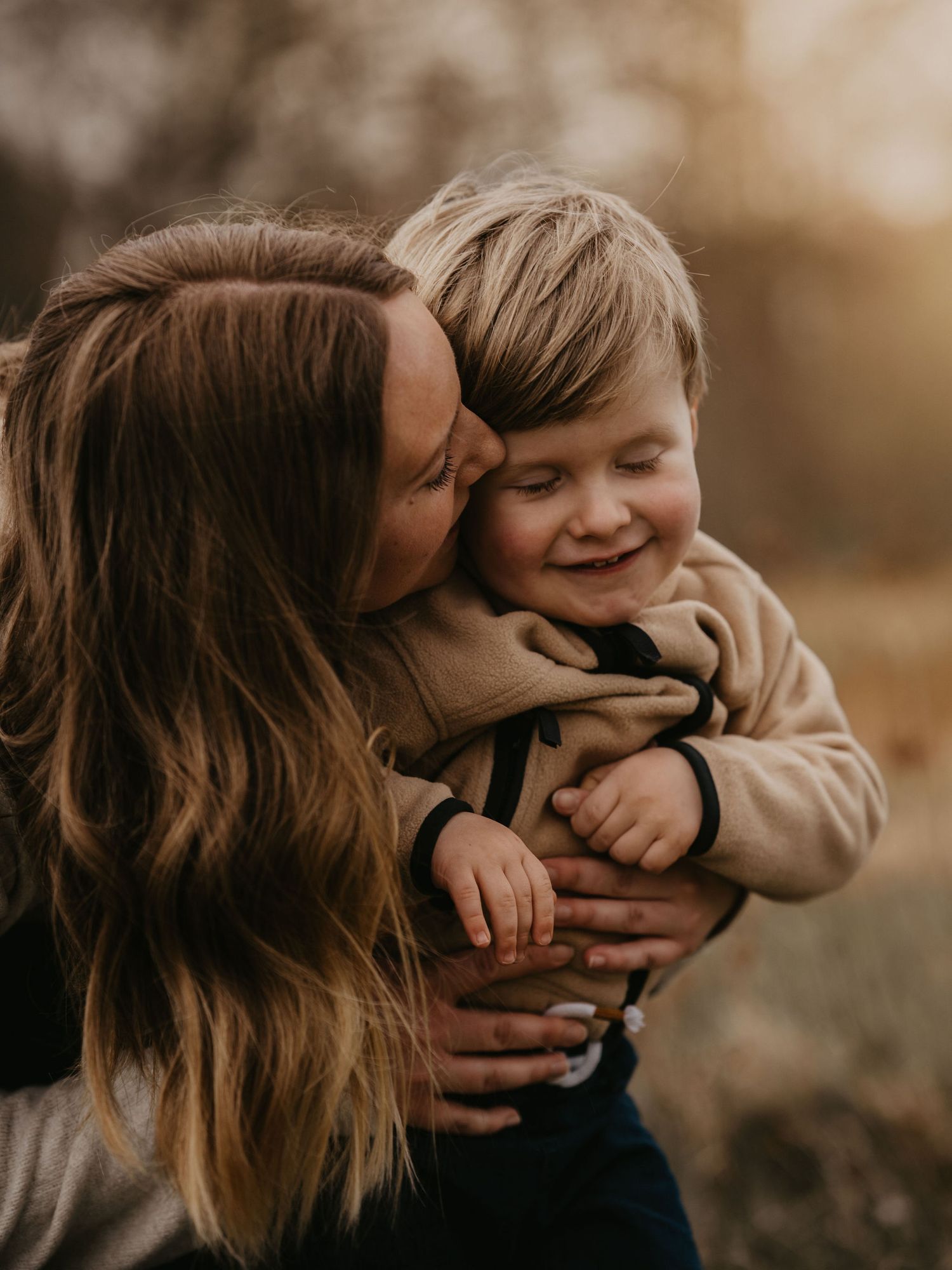 An intimate family portrait showing affection and joy during a warm autumn afternoon outdoors.