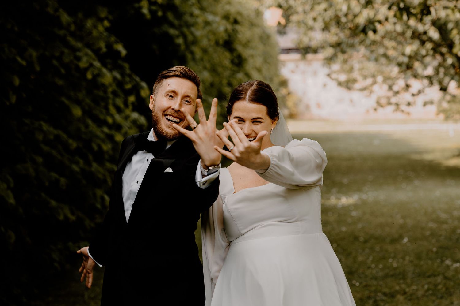 A newlywed couple shares joyful moments together during their outdoor wedding photoshoot in a natural setting.