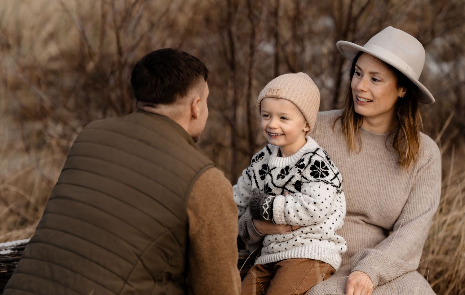 Candid family moment outdoors with everyone wearing coordinated neutral winter outfits.