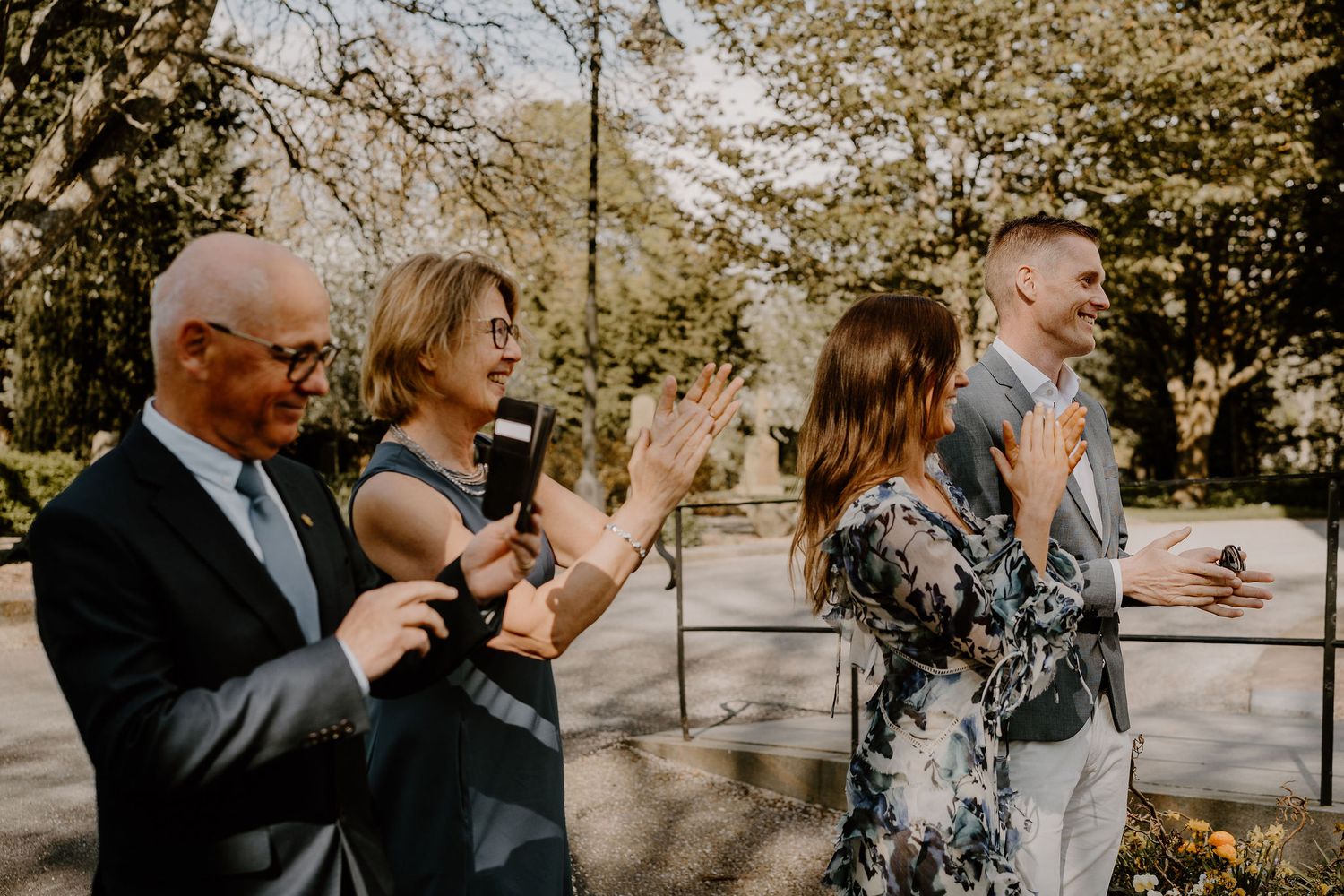 Emotional group candid moment captured during an outdoor event with sunlit scenery.
