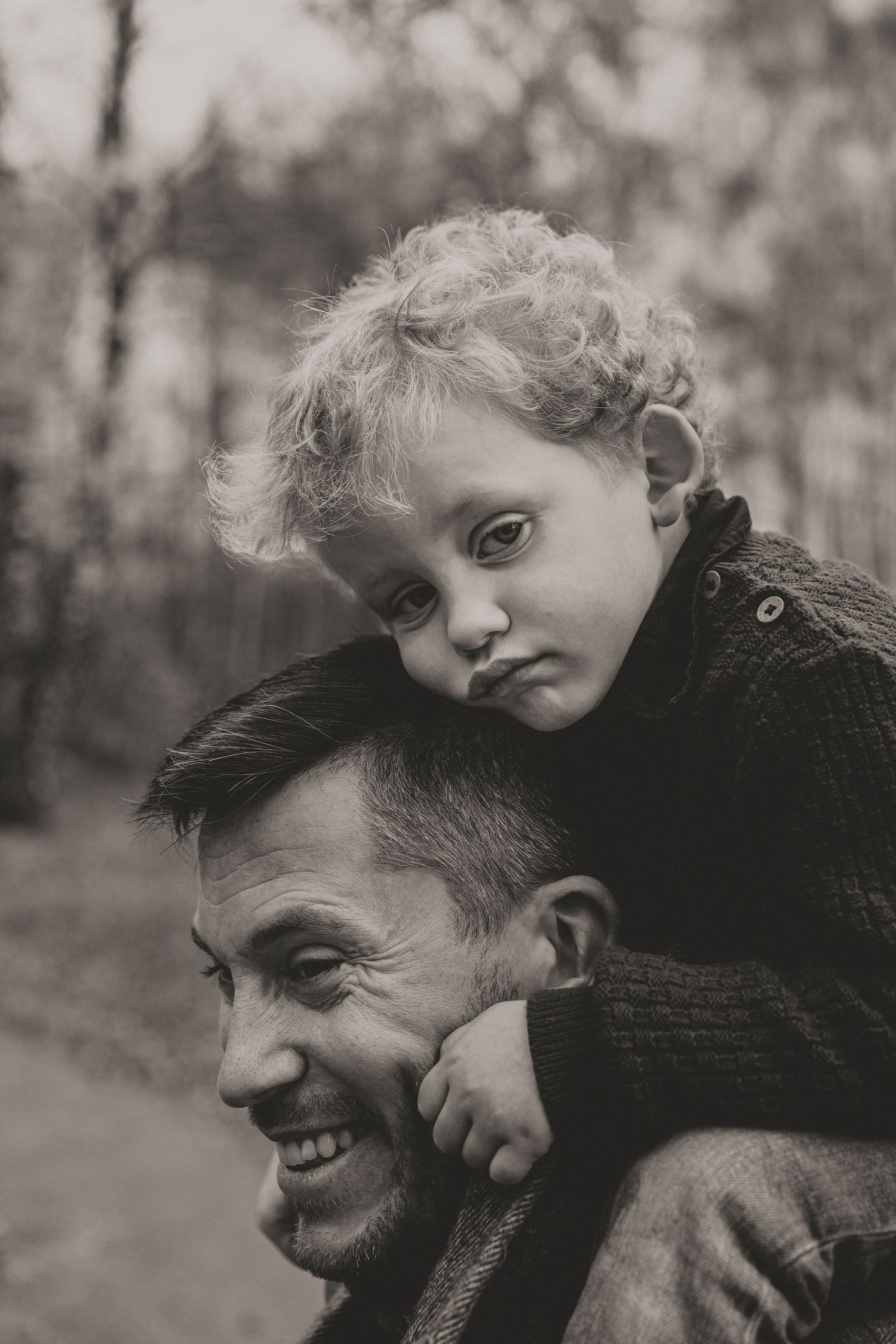 Black and white portrait of a parent and child sharing a joyful outdoor moment together in nature.