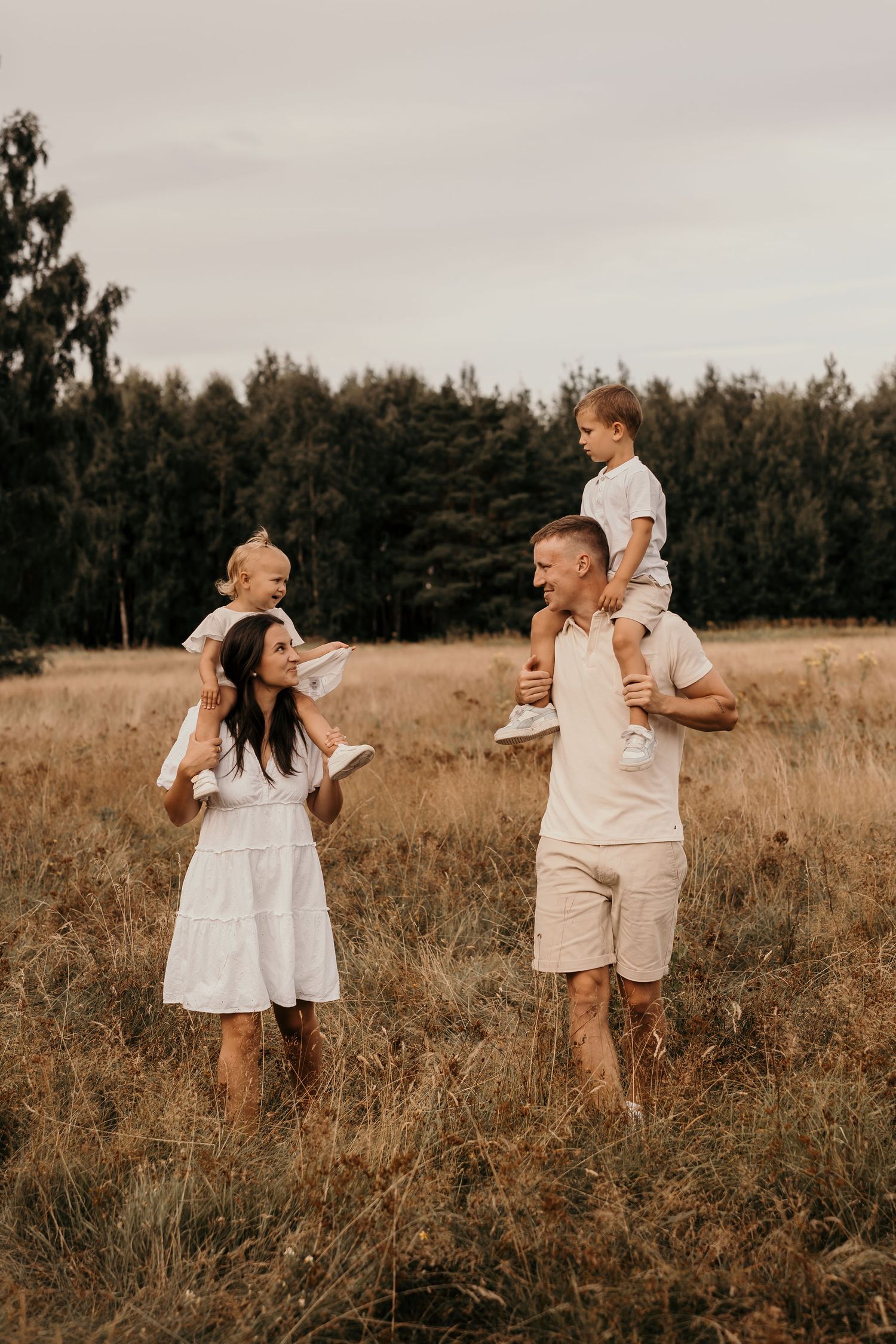 Family enjoying playful moments together in a golden field at sunset.