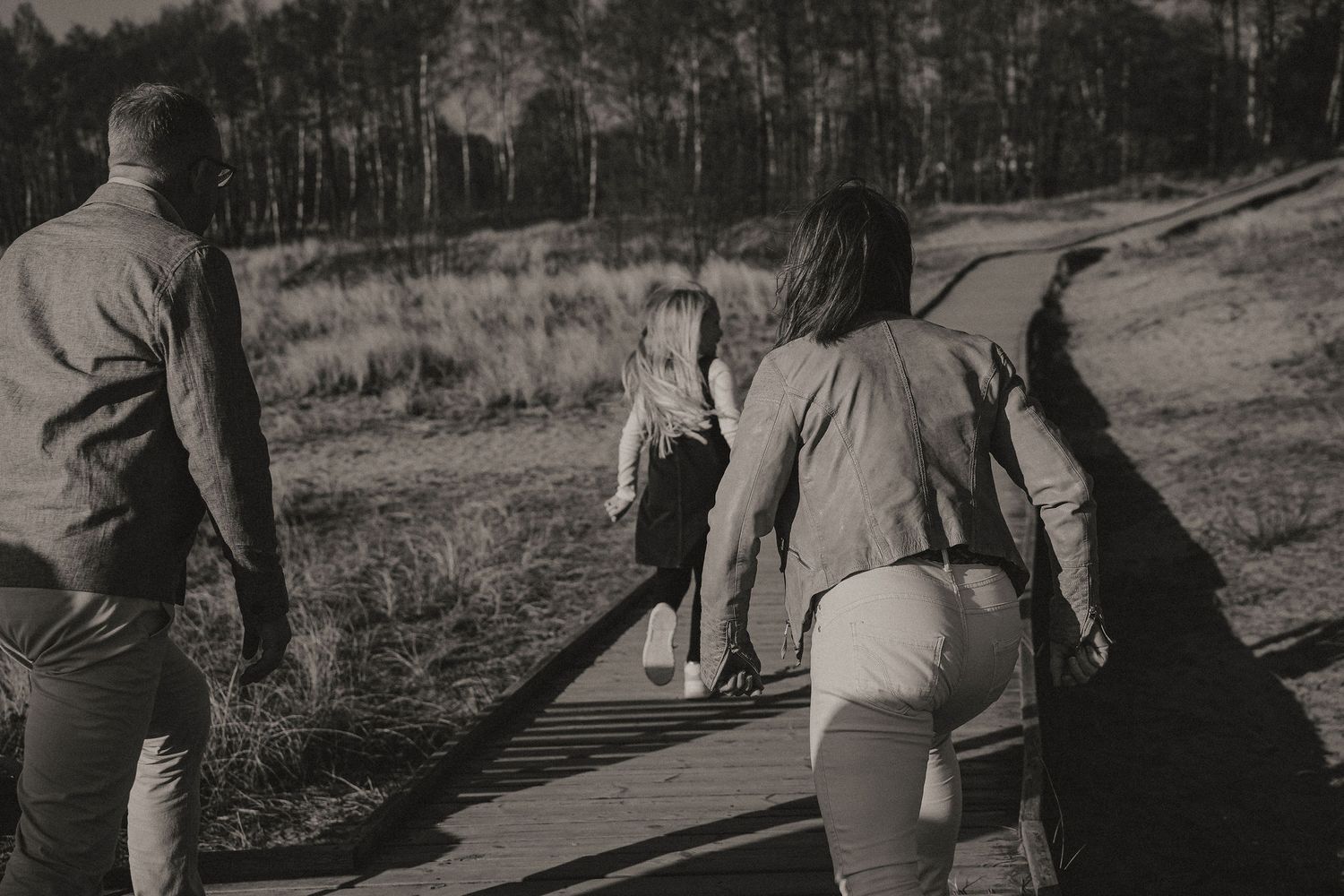 Group walking together along a winding path through grassy fields with trees in the distance.