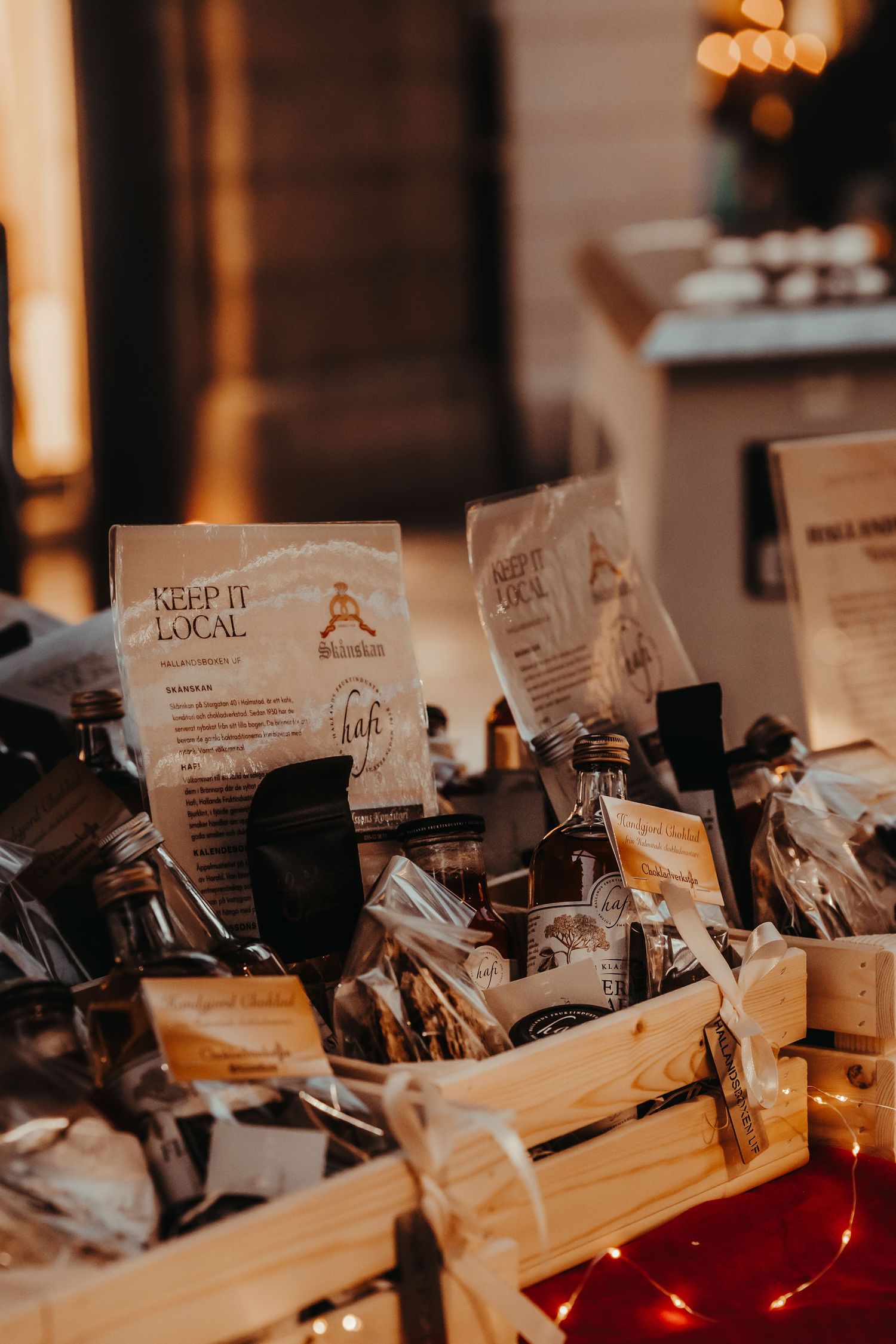 Artisanal coffee bags and products arranged in wooden crates with warm lighting at a local market display.