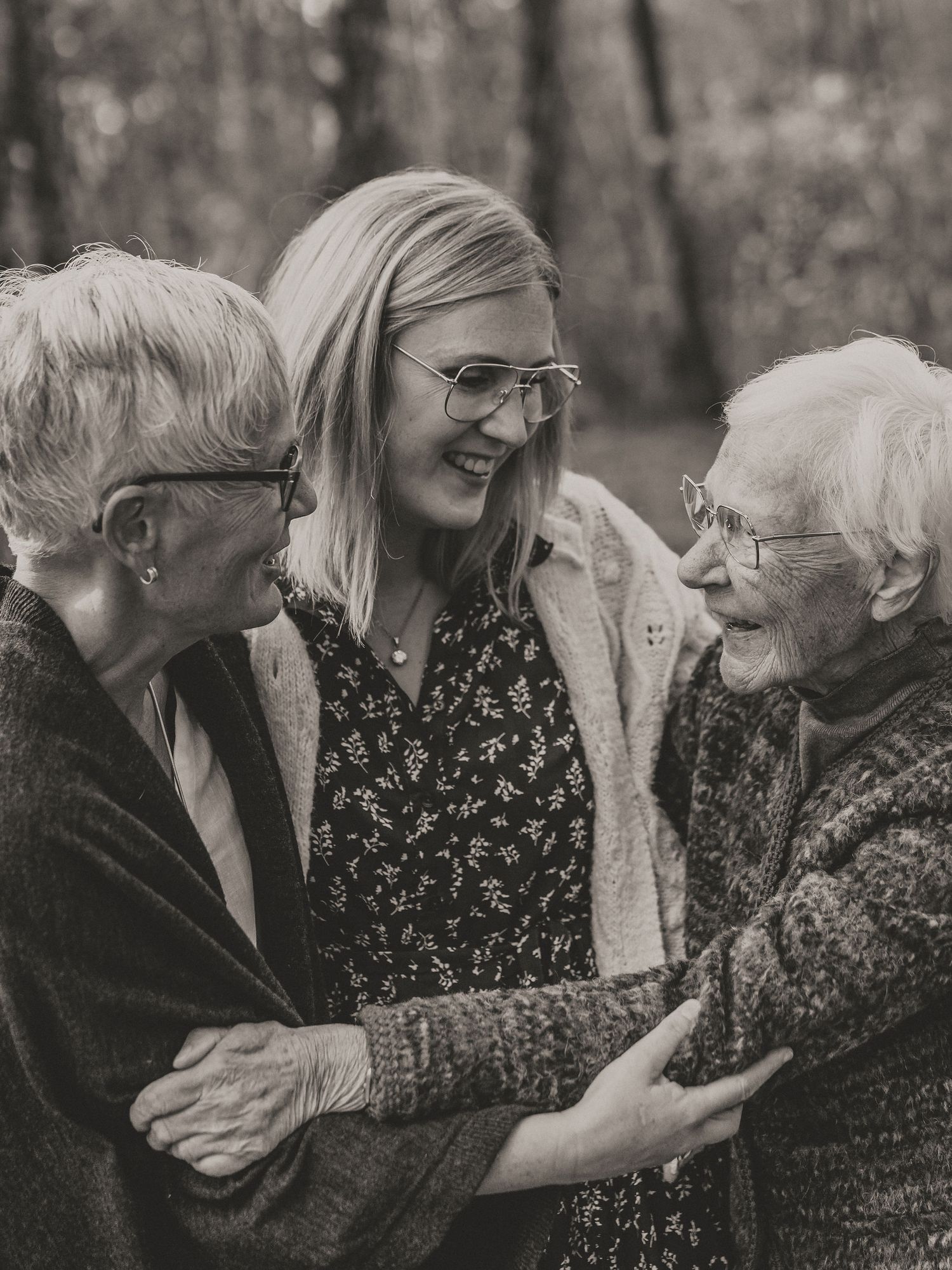 Three generations share a joyful moment together in a black and white photo taken outdoors in nature.