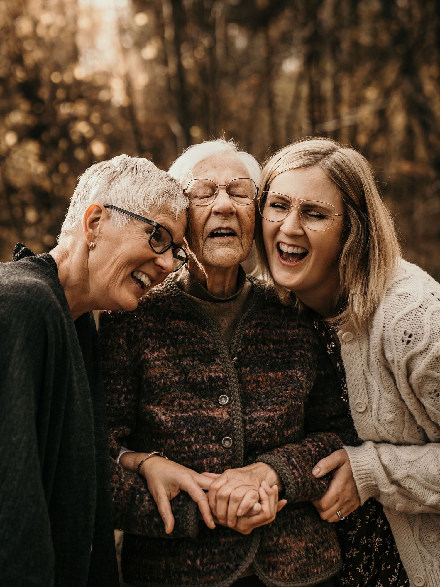Three generations share a heartfelt moment of laughter and joy together in a warm autumn setting, wearing cozy sweaters.