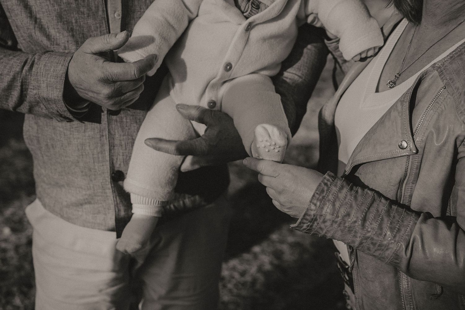 A vintage black and white photograph showing two people exchanging cigarettes in a casual outdoor setting.
