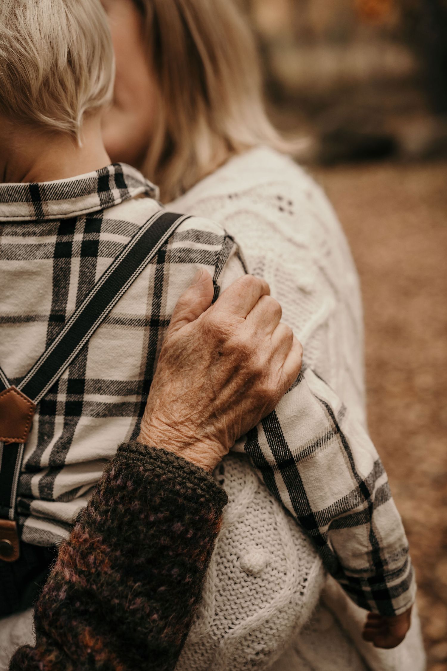 Close-up of hands showing generational connection through touch and texture of clothing.