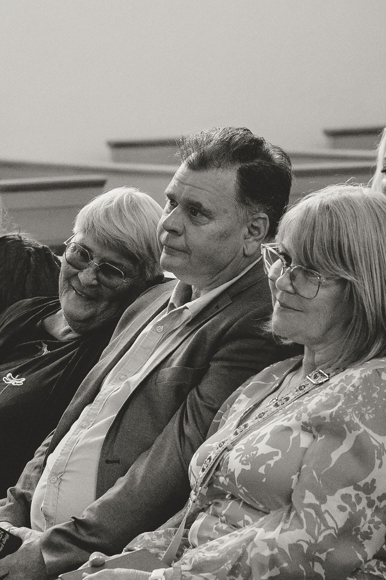 Three people seated together at an event in black and white photography.