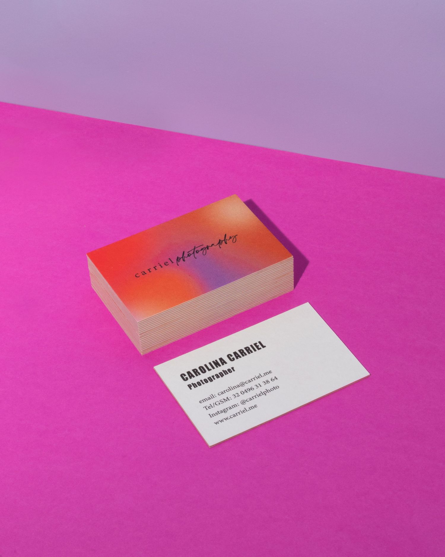 Colorful gradient business cards for Carolina Carbiel Photography displayed on a vibrant pink surface.