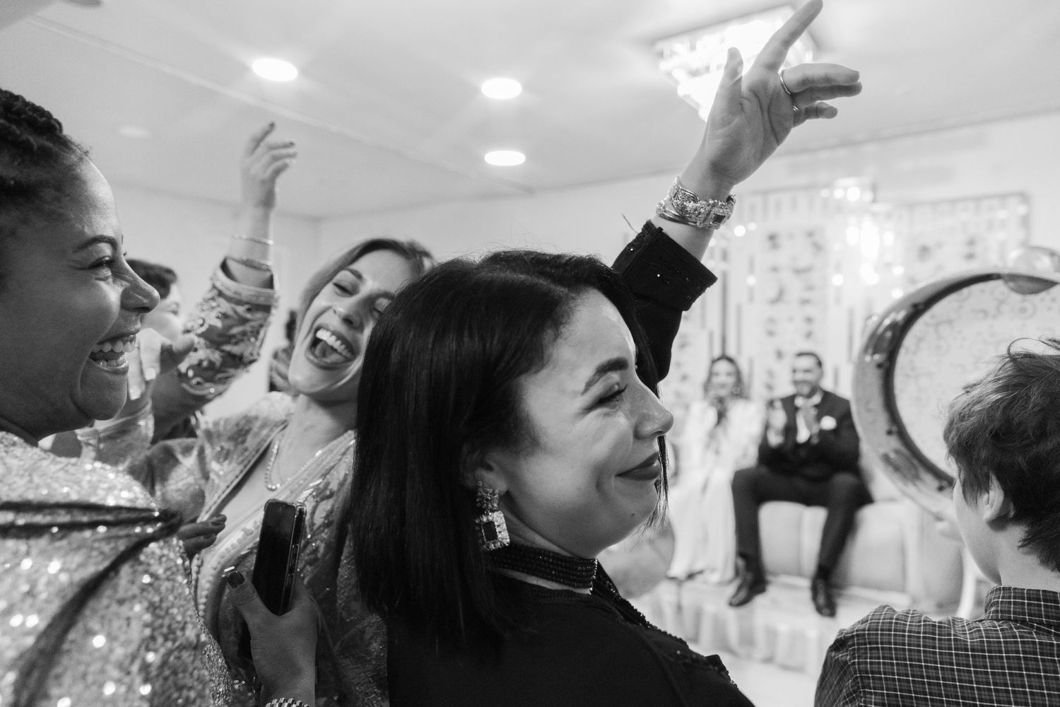 Group of women laughing and celebrating together at a festive party event in black and white.